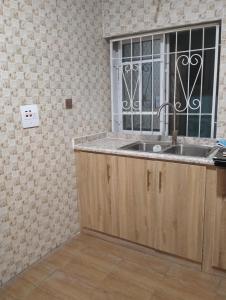 uma cozinha com um lavatório e uma janela em Dazzle Hotels and Apartments Riverpark em Rubuchi