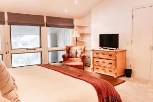 Schlafzimmer mit einem Bett, einem TV und einem Stuhl in der Unterkunft The Ski In Ski Out Condo in Ketchum