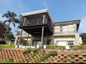 Casa grande con balcón en la parte superior de una pared en Millwood House en Durban
