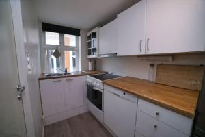 cocina con armarios blancos y encimera de madera en Vestre Murallmenningen, en Bergen