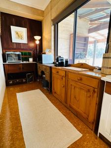 una cocina con armarios de madera y una gran ventana en Rammed Earth Retreat en Wagin