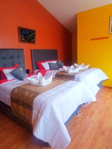 two beds in a room with orange walls at Sumac wasi in Chivay