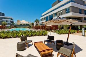 Un patio con una mesa y sillas y una sombrilla. en Condominio Quay Luxury, en Florianópolis