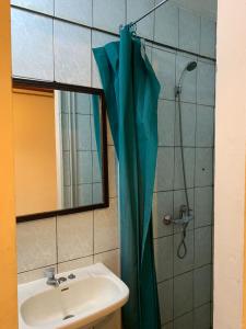 uma casa de banho com um lavatório e um chuveiro com uma cortina de chuveiro azul em Residencial La Piramide em Iquique