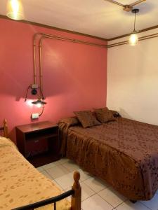 um quarto com duas camas e um candeeiro na parede em Residencial La Piramide em Iquique