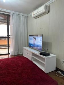 Vila de Ofir recreio dos Bandeirantes 200m da Praia في ريو دي جانيرو: غرفة معيشة مع تلفزيون على مكتب أبيض