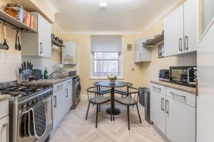 a kitchen with white cabinets and a small table at property discarded in London