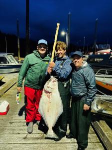 a group of three people holding a fish and a bat at The Old Schoolhouse Lodge and Cabins in Coffman Cove