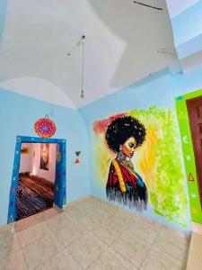een schilderij van een vrouw aan een muur in een kamer bij Nukud guest house in Aswan