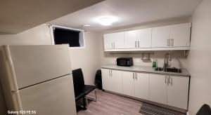 a small kitchen with white cabinets and a refrigerator at Home away from home - 6 bedroom fantastic bungalow in Winnipeg