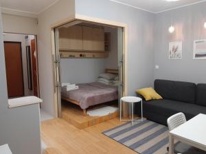 ein Wohnzimmer mit Sofa und Bett in der Unterkunft Studio Głębocka 56 in Warschau