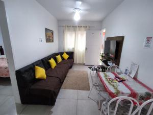 - un salon avec un canapé noir et des oreillers jaunes dans l'établissement Cond Cristal Indaiá I Ap23, WI-FI, 450m praia Indaiá, check-out 16h, à Bertioga