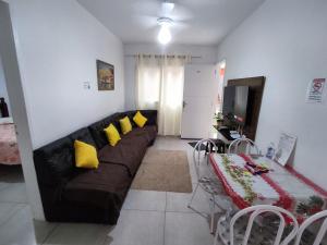 a living room with a black couch and yellow pillows at Ap23 Cristal do Indaiá I 450m praia in Bertioga
