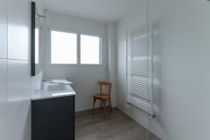 ein Badezimmer mit einem Waschbecken, einem Stuhl und einem Fenster in der Unterkunft KER STIVELL - Superbe maison neuve à 2 pas de la mer in Landunvez