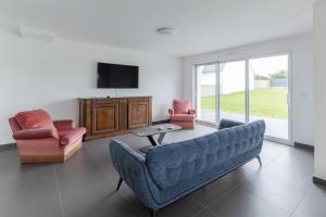 ein Wohnzimmer mit einem Sofa, 2 Stühlen und einem TV in der Unterkunft KER STIVELL - Superbe maison neuve à 2 pas de la mer in Landunvez