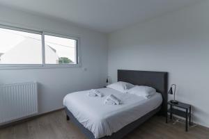 a bedroom with a bed with white sheets and a window at KER STIVELL - Superbe maison neuve à 2 pas de la mer in Landunvez