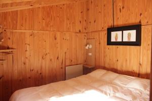 Un dormitorio con una cama en una pared de madera. en Cabaña El Bosquecito con vista al dique, en Potrerillos