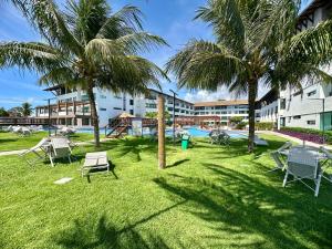 een park met stoelen en palmbomen voor een gebouw bij Flat Luxo - Pé na Areia - Maui Beach Residence in Tamandaré