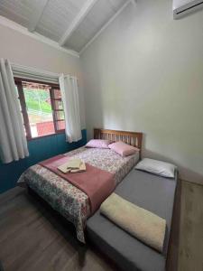 a bedroom with two beds and a window at Jardins da Vila - Farm house in Blumenau