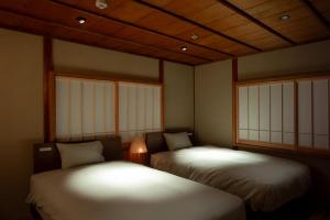 Zimmer mit 2 Betten in einem Zimmer mit Fenstern in der Unterkunft willow. in Toyooka