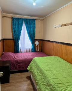 1 dormitorio con 2 camas y ventana en Casa central en Punta Arenas, en Punta Arenas