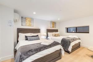 two beds in a bedroom with white walls and windows at Bellevue Splendor Fern Suite BY Betterstay in Bellevue