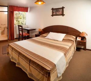 a bedroom with a large bed with a desk and a bathroom at Hotel Benavides in Arequipa