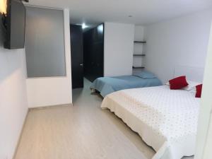 1 dormitorio con 2 camas y espejo en Lujoso Hospedaje en las Alturas, en Tunja
