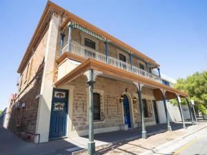 een oud bakstenen gebouw met een balkon in een straat bij Base Camp Hostel in Adelaide