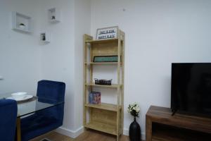 a book shelf in a living room with a tv at Luxe & Stylish Central Luton 2Bed Apt - Fast Wi-Fi & Private Patio in Luton