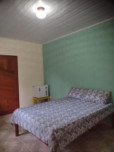 um quarto com uma cama e uma parede verde em Pouso AJH em Paraty