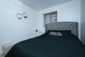 a bedroom with a bed with a black comforter at Luxe & Stylish Central Luton 2Bed Apt - Fast Wi-Fi & Private Patio in Luton
