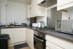a kitchen with white cabinets and a stove top oven at Luxe & Stylish Central Luton 2Bed Apt - Fast Wi-Fi & Private Patio in Luton
