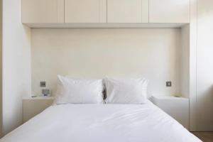 un letto bianco con lenzuola e cuscini bianchi di The Tonic in Shoreditch a Londra
