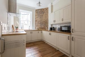 a kitchen with white cabinets and a brick wall at 3 Bedroom in the Heart of West End in London