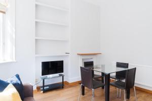 a dining room with a table and chairs and a tv at PER-64 64 Perham Road in London