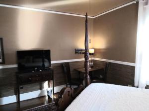1 dormitorio con 1 cama, TV y mesa en Black Lantern Inn, en Roanoke
