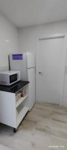 cocina blanca con microondas y nevera en Apartamento Agradables 3, en Madrid