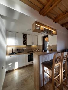 a kitchen with white cabinets and a table and chairs at Brvnara Pogled Zlatara in Nova Varoš