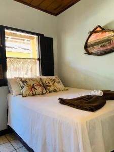 um quarto com uma cama com lençóis brancos e uma janela em Pousada Três Corações em Arraial d'Ajuda