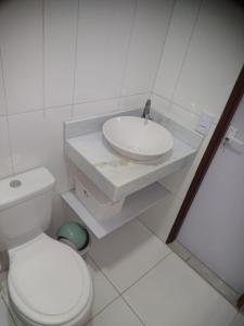 Baño blanco con lavabo y aseo en Pouso AJH, en Paraty