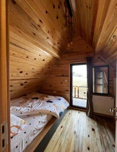 Bett in einem Holzzimmer mit einem großen Fenster in der Unterkunft Brvnara Pogled Zlatara in Nova Varoš