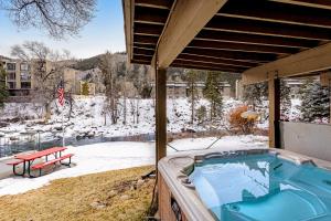 a hot tub on a patio with snow on the ground at Eagle River Retreat in Avon