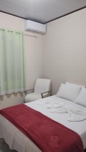 um quarto com uma cama branca e 2 cadeiras em Casa tia Rosa hospedagem familiar em Guapimirim
