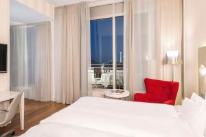 a bedroom with a white bed and a red chair at NH Collection Berlin Mitte Friedrichstrasse in Berlin