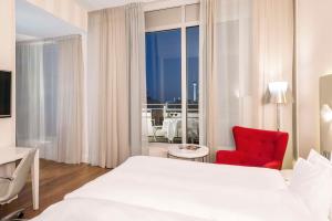 柏林的住宿－柏林米特弗里德里希NH精選酒店，卧室配有白色的床和红色椅子