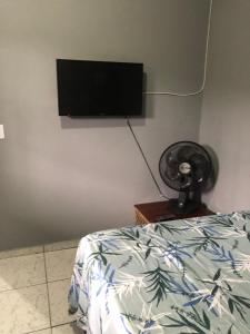 a bedroom with a bed and a flat screen tv on the wall at Kitnet do Costa Praia do Pereque Guaruja!!! in Guarujá