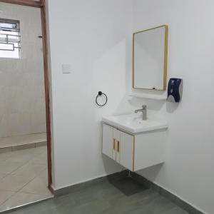 ein weißes Badezimmer mit einem Waschbecken und einem Spiegel in der Unterkunft Jade luxury apartments Diani in Mombasa