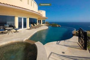 a house with a swimming pool next to the ocean at Cliffside 8BR Villa with Breathtaking Views - Pool in Cabo San Lucas