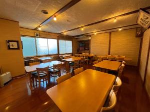 un restaurante vacío con mesas y sillas de madera en Oyado Uchidaya, en Nozawa Onsen